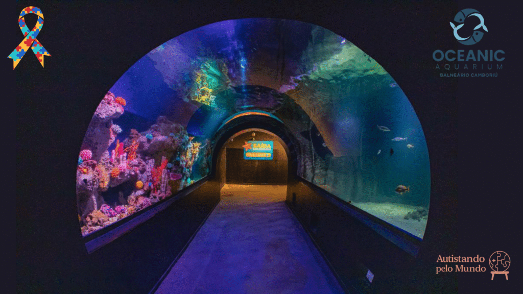 Túnel de vidro do Oceanic Aquarium em Balneário Camboriú, com vista subaquática de corais coloridos e peixes, destacando ambiente acessível e sensorialmente tranquilo para autistas.