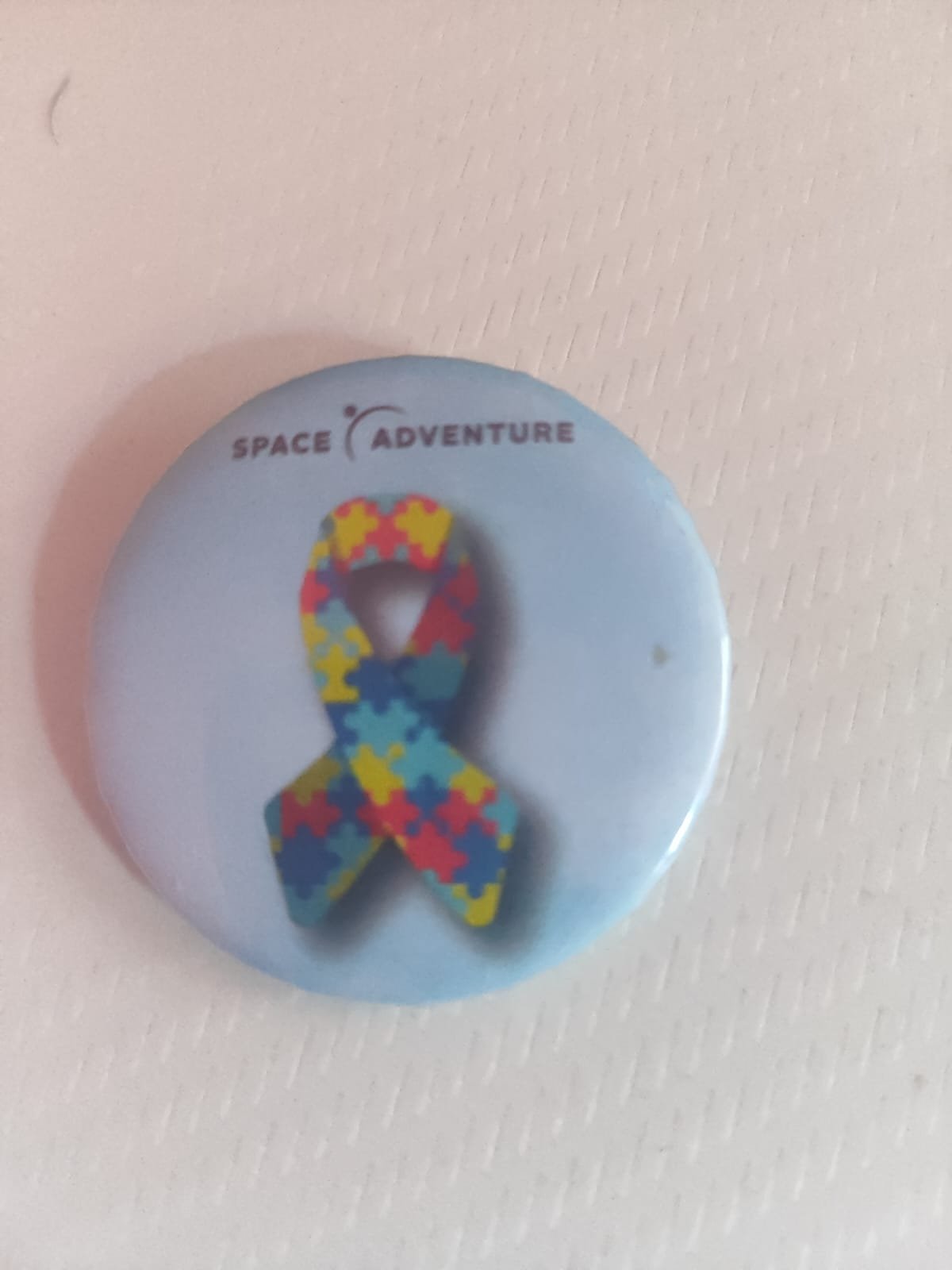 Bottom de identificação com laço do autismo recebido no Space Adventure Balneário Camboriú